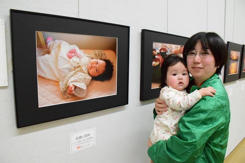 「お食い初め」の写真を出品した丹羽さんと長女の汐俐ちゃん＝茂原市立美術館・郷土資料館
