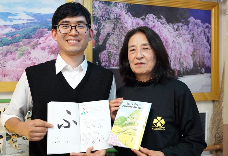 英語版ひらがなの書き方本を紹介する金子さん（右）と子川さん＝勝浦市