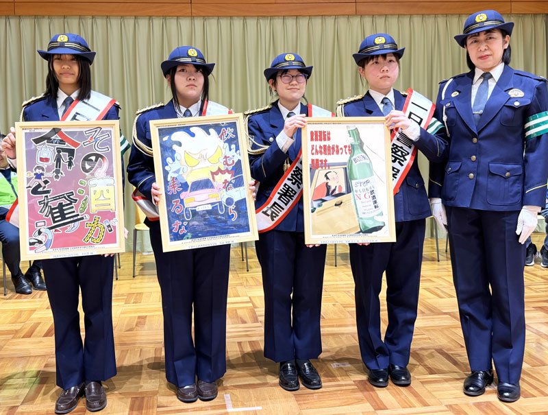 春の全国交通安全運動出動式で飲酒運転撲滅ポスターを披露する一日署長の高校生（左４人）と石崎署長＝君津市