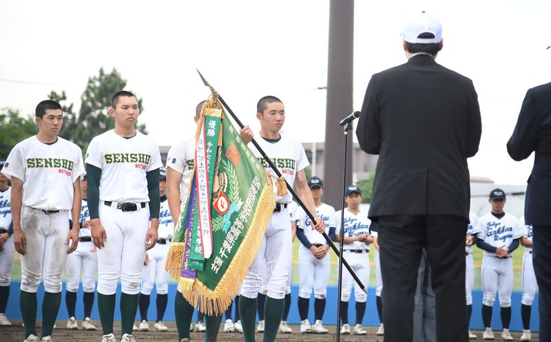 史上初の春季千葉県大会４連覇を果たし、優勝旗を受け取る専大松戸の高貝主将（右）＝３日、千葉市の県総合スポーツセンター野球場　森大輔撮影