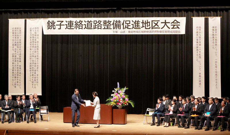 銚子連絡道路整備推進地区大会で要望書を手渡す米本会長（中央左）＝２０日、旭市の県東総文化会館