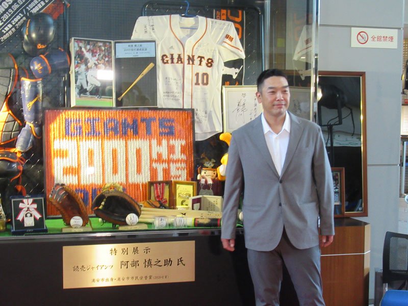 自身の記念品展示ブースを前に笑顔の阿部慎之助さん＝２０２２年７月、浦安市