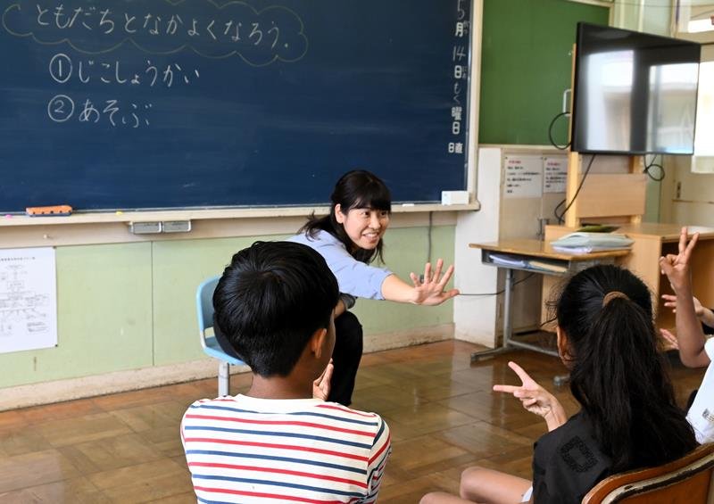 日本語指導が必要な児童２人（手前）にじゃんけんについて教える担当教諭＝５月１４日、富里市
