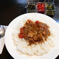 人気のポーク&トマトカレー（７００円）。付け合わせ（グリーンペッパー、福神漬け、ピクルス）は、宝石箱のような容器で提供される