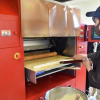 オーブンで真剣な表情でバウムクーヘンを焼く店長の前田さん
