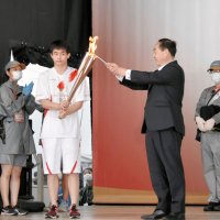 山武市の松下浩明市長（右）からトーチに火を灯される錦織孟徳さん
