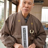 数十年ぶりに版木から刷った疫病よけお守り札を持つ前住職の椎名さん
