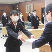 千葉興業銀行の入行式で梅田頭取（右）から辞令を受け取る新入行員＝１日、千葉市美浜区