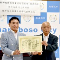 支援承認書を掲げる日枝神社拝殿修復事業実行委の国府田会長（右）と東日本鉄道文化財団の太田専務理事