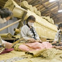 しめ縄に使うわらを丁寧に編み込む成田山新勝寺の奉仕員＝１日、成田市