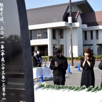 慰霊碑に献花して手を合わせるトリプルアイプロジェクトのメンバーら