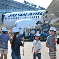 燃料を給油中の航空機を前に写真撮影して楽しむ親子＝成田空港