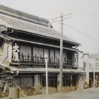 大正末～昭和初期ごろの大屋旅館。出入り口付近に乗合自動車発着所の看板が掲げられ、右手奥には大屋旅館自動車部の看板と小型車が見える（大屋旅館提供）