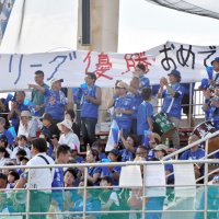 １部初優勝が決まり、横断幕を掲げて選手を祝福するオルカのサポーターたち＝１日、鴨川市
