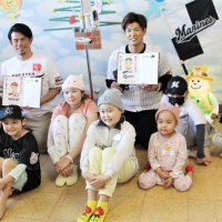 贈られたメッセージ入りカレンダーを見せて記念撮影する楽天の今江監督（後列左）、千葉ロッテの中村選手（同右）と子どもたち＝２１日、千葉市緑区
