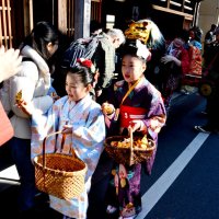 佐原の町並みに繰り出し、観光客らに折り鶴を配る子どもと獅子舞の一行