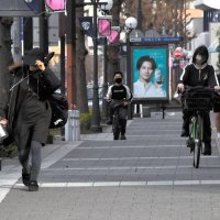 強風の中、帽子を押さえて歩く人ら＝１５日午後２時４０分ごろ、千葉市中央区