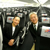 少女が夢に向かって走るイラストのロゴが施された座席に座る高橋社長（左）と西田社長