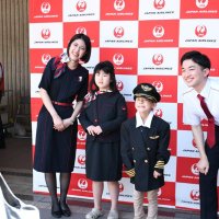 地上係員（左右）と一緒にパイロットと客室乗務員の制服を着て記念撮影を楽しむ子どもたち＝１８日、成田市の成田空港

