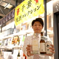 県産の材料を使って作った「成田空港エール」とオリジナルのジンを紹介する成田空港の土産店スタッフ＝成田市