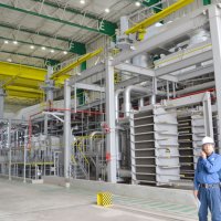 ８月から稼働する１号機の建屋内で、高効率発電設備について説明する佐藤社長