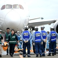 航空機内から救助された人を担架で運ぶ訓練の参加者ら＝成田市の成田空港