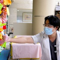 ツリーを織りなす折り紙作品を手に取る県こども病院医師の佐久間昭利さん