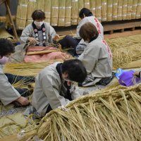 細いしめ縄を丁寧に編んでいく成田山新勝寺の奉仕員ら＝１日、成田市