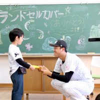木村投手（右）からランドセルカバーを受け取る新１年生