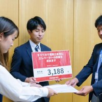 県教委の担当者（右）に集めた署名を提出した松井さん（署名サイトのＣｈａｎｇｅ．ｏｒｇ　Ｊａｐａｎ提供）＝５月、県庁
