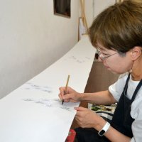 糊の輪郭の中に筆で一つ一つ色を入れていく「色挿し」と呼ばれる工程の様子
