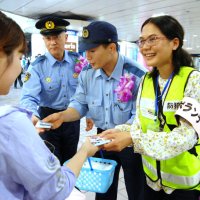 警察官と一緒に反射材などを配る留学生
