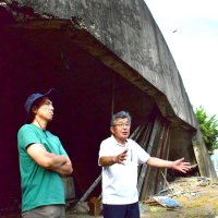 掩体壕の前で伝え聞いた戦中の様子を語る石井定夫さん（右）と知彦さん

