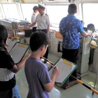 操舵室で船の仕組みについて説明を受ける子どもたち＝富津市沖