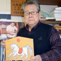 白馬の絵馬を持つ矢部さん。矢部さんの絵馬は県伝統的工芸品に指定されている