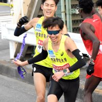 ２区・市川大世にたすきを渡す中央学院大の１区・近田陽路（中央奥）＝２日、神奈川県横浜市の鶴見中継所