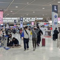 国際線を利用する旅客でにぎわう成田空港。スーツケースに荷物を収納し直す姿も見られる＝成田市