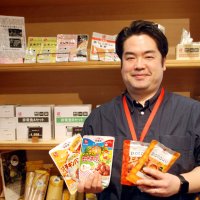 能登半島地震の際、被災地支援で提供した食料品を持つ佐々木さん＝３月１２日、船橋市の石井食品
