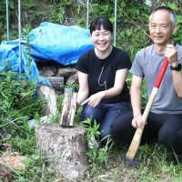 別荘の庭で、シロマダラが見つかったまきを手にする木下有為子さん（左）と芳郎さん＝南房総市
