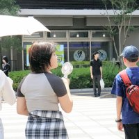 気温が上昇する中、日傘やハンディーファンで暑さ対策をする人々＝１８日午後、千葉市中央区